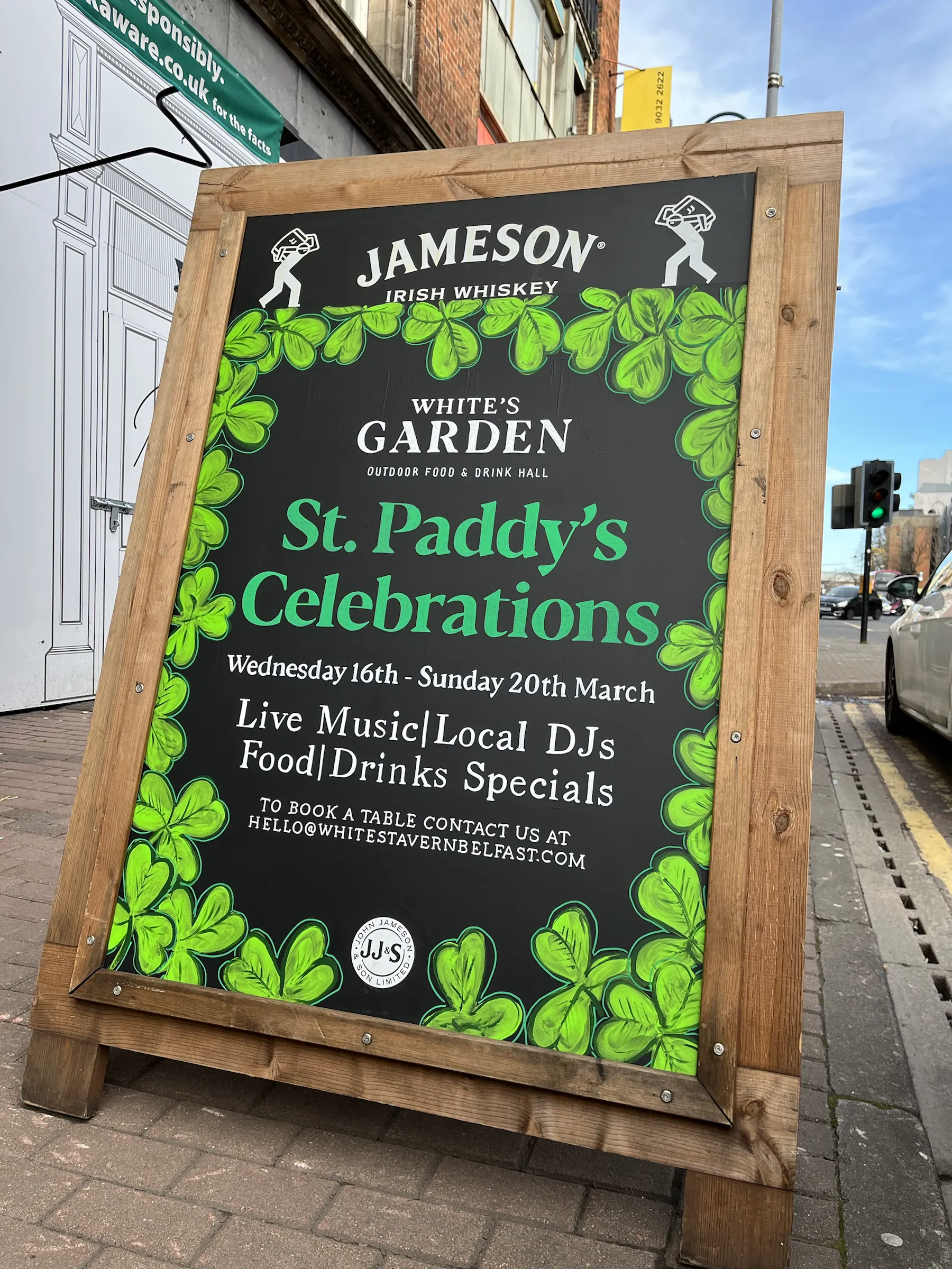 A wooden A-board for White’s Garden, its black panel framed in painted shamrocks and advertising St. Paddy’s celebrations with live music, local DJs and food and drinks specials.