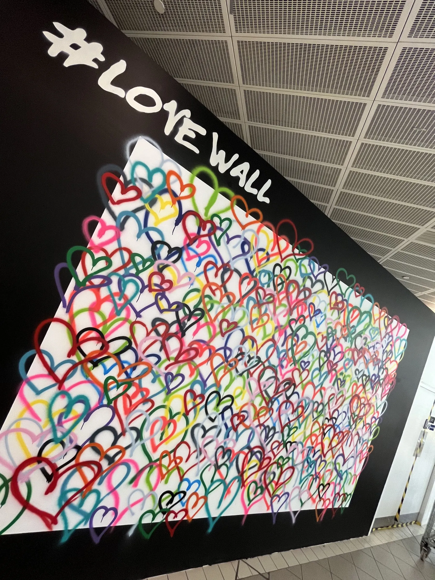 A close angle on the #LoveWall’s white lettering and layered spray-painted hearts.