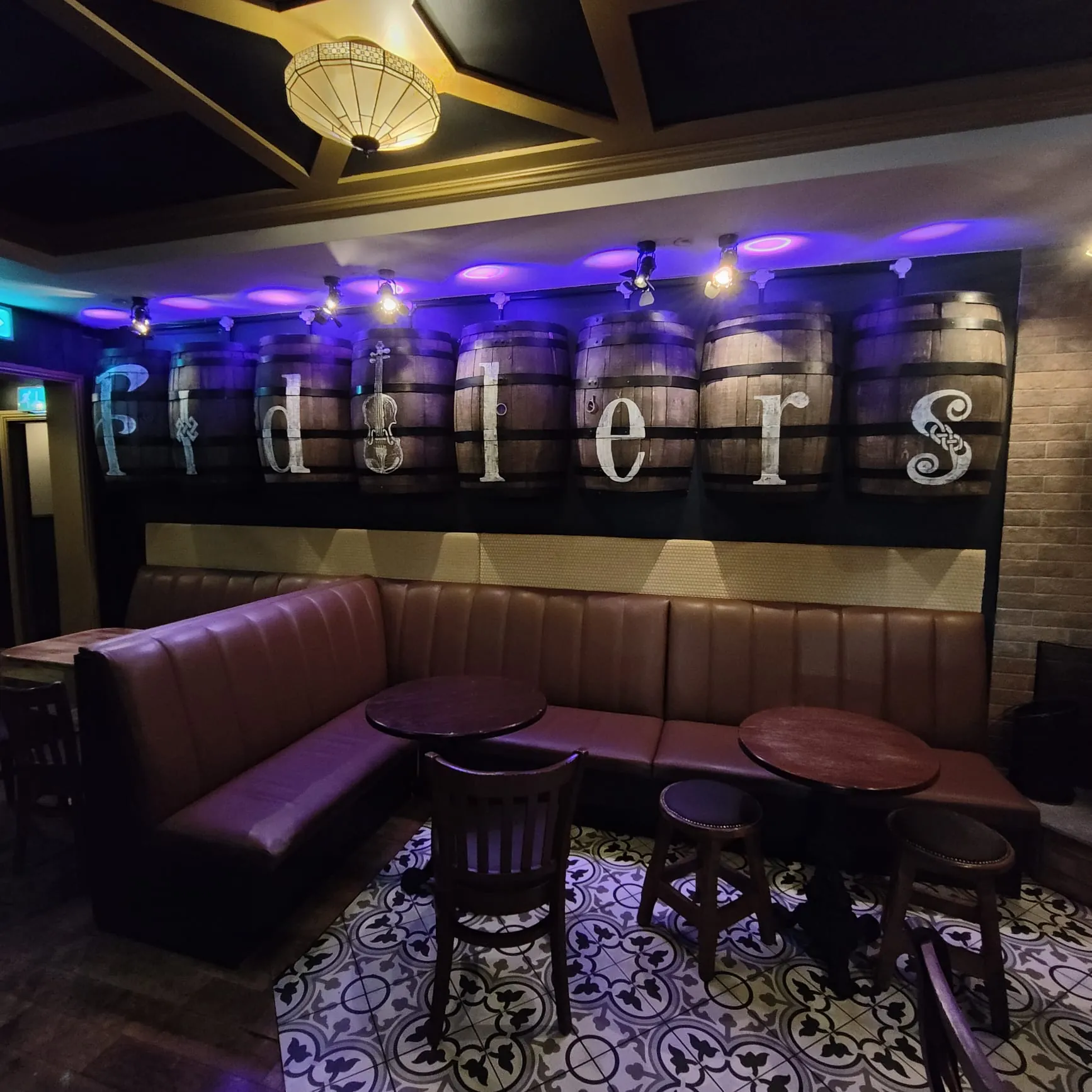 Whiskey barrels above the booths, each painted with one letter of “Fiddlers”.