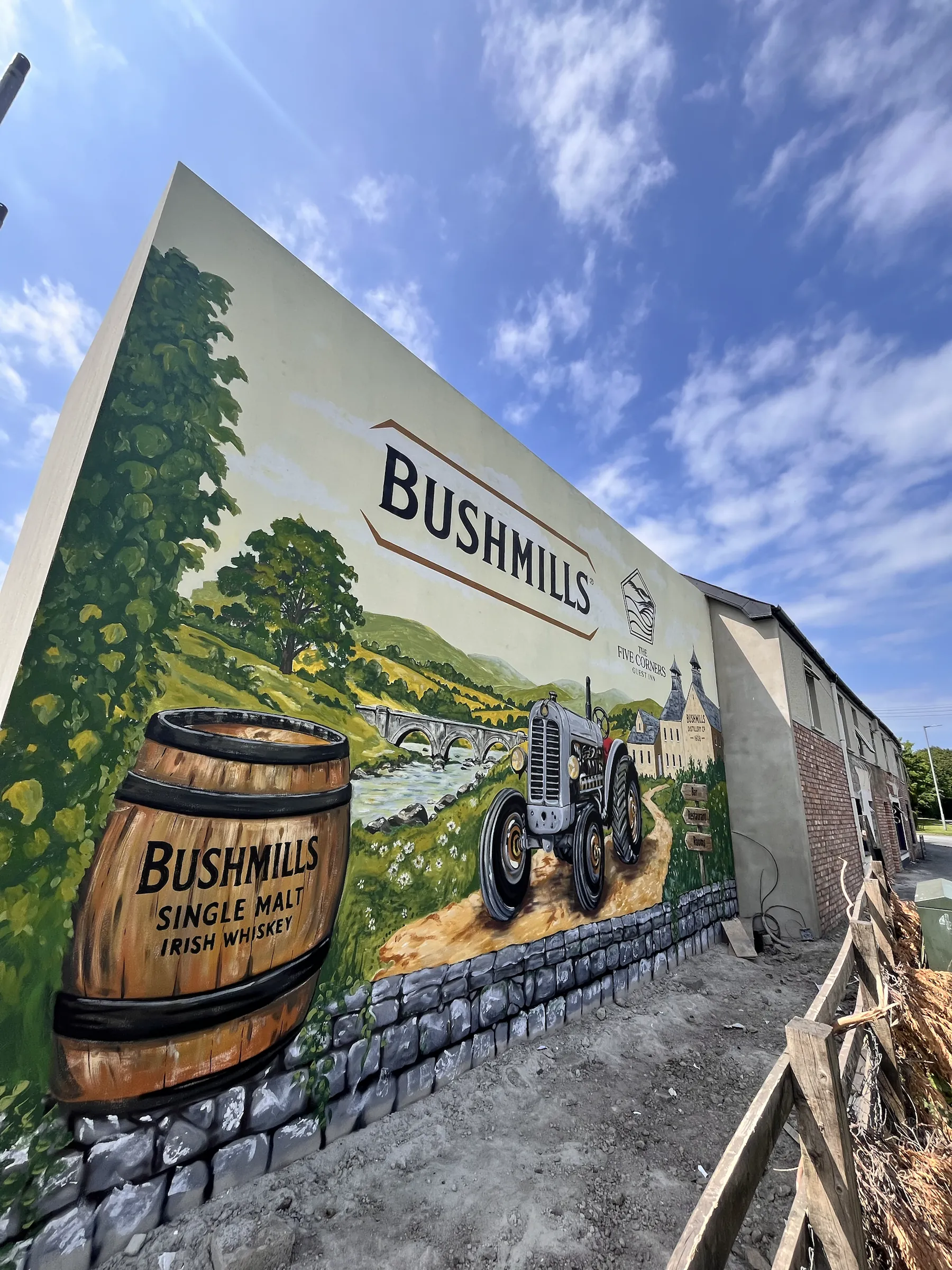 The finished mural seen along the gable: a barrel of Bushmills single malt, a river and a grey tractor.