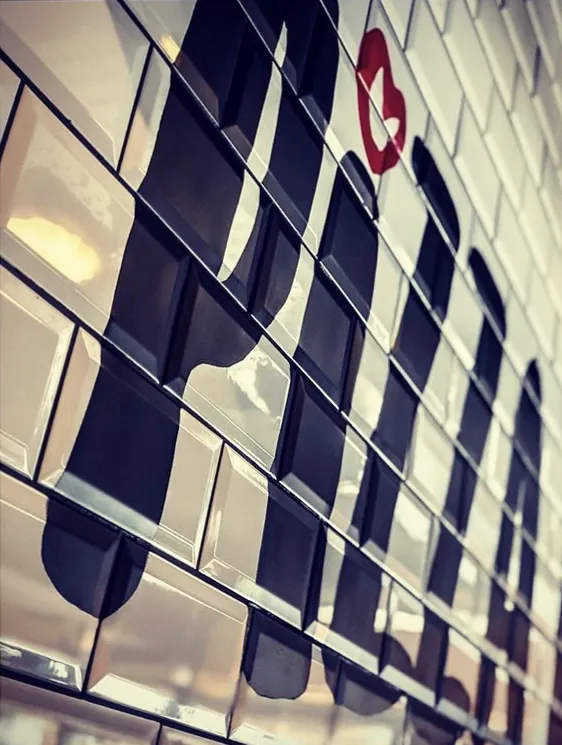 A close-up of large black lettering painted across white bevelled wall tiles, with a small red heart.