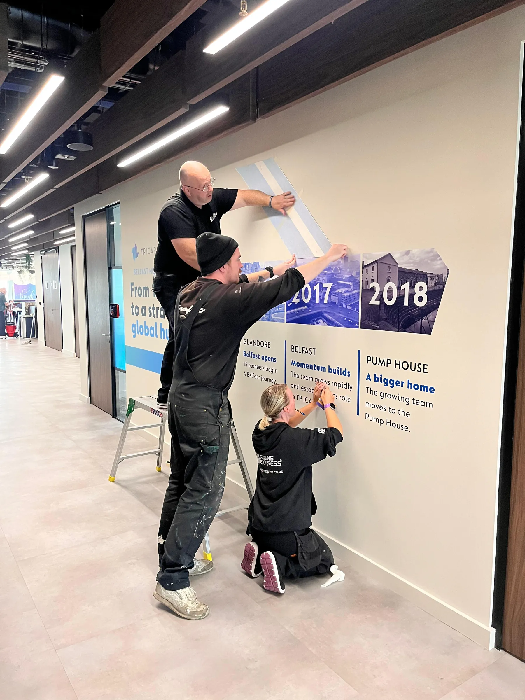 Three painters working together on the timeline wall’s panels for 2017 and 2018.