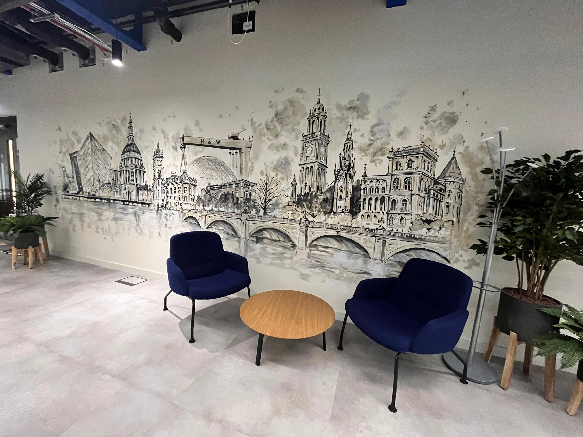 The finished skyline mural behind a seating area of blue armchairs and a round table.