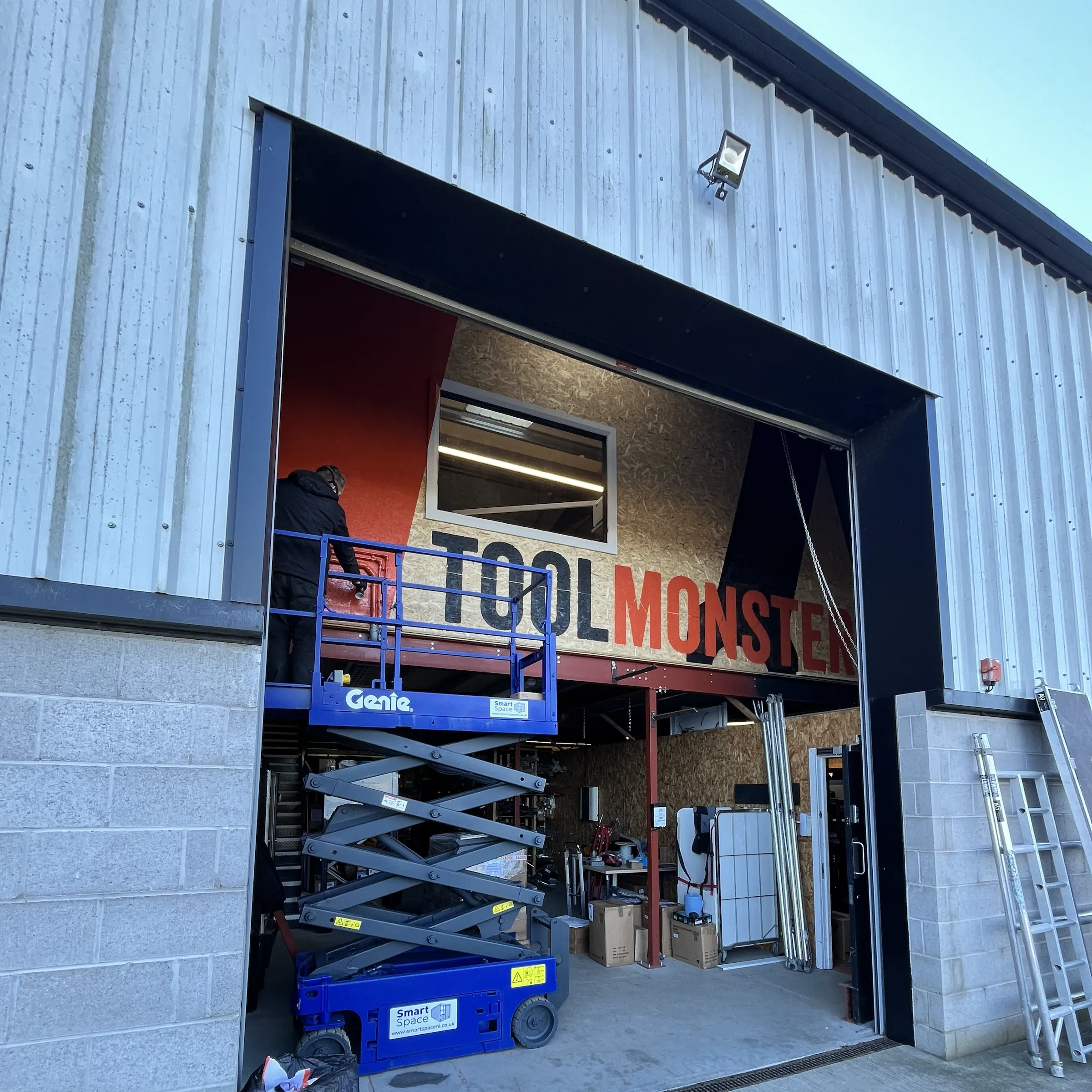 Tool Monster’s orange and black lettering painted inside the workshop, seen through the open loading bay.