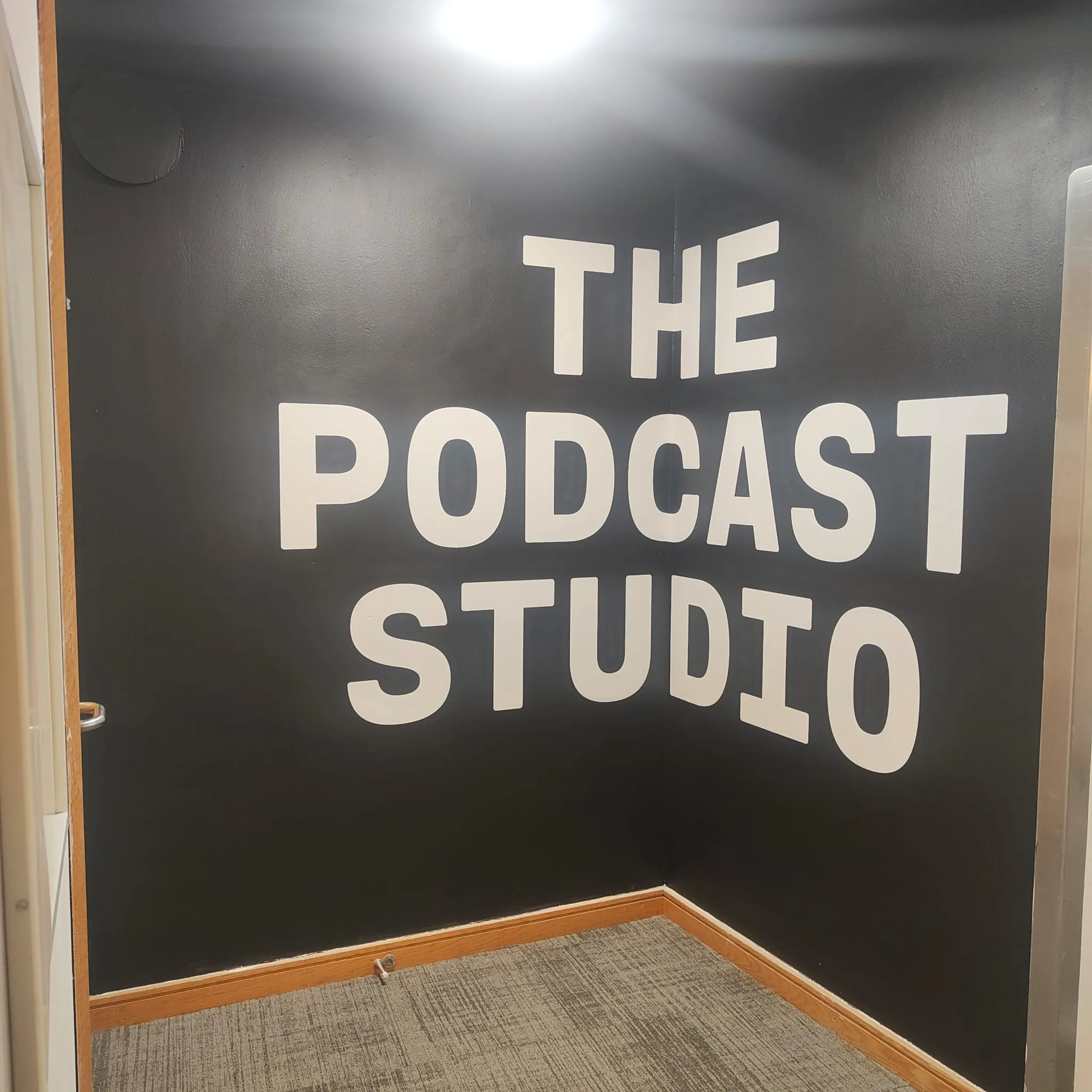 “The Podcast Studio” painted in huge white capitals across a black wall.